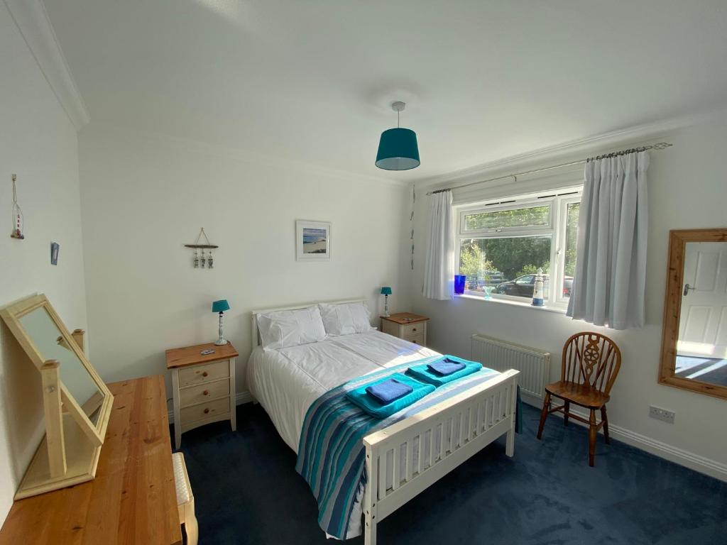 een slaapkamer met een bed, een tafel en een raam bij Agapanthus Bed & Breakfast - Fraddam in Hayle