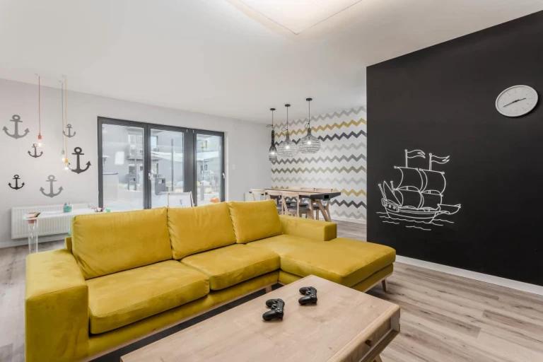 ein gelbes Sofa im Wohnzimmer mit einem Tisch in der Unterkunft KOŁOBrzegu Apartamenty by Jantar Apartamenty Kołobrzeg in Kołobrzeg