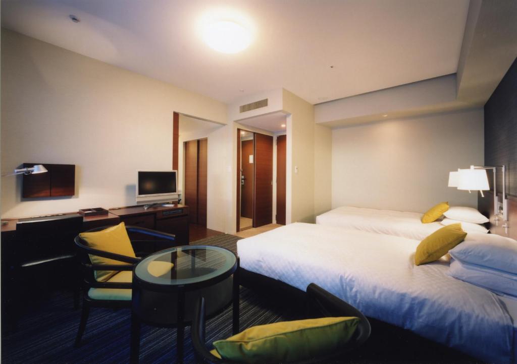 a hotel room with two beds and a desk at Centrair Hotel in Tokoname