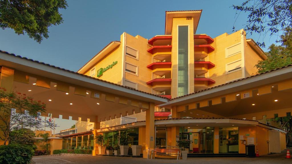 un gran edificio amarillo con balcones rojos. en Holiday Inn Cuernavaca, an IHG Hotel, en Cuernavaca