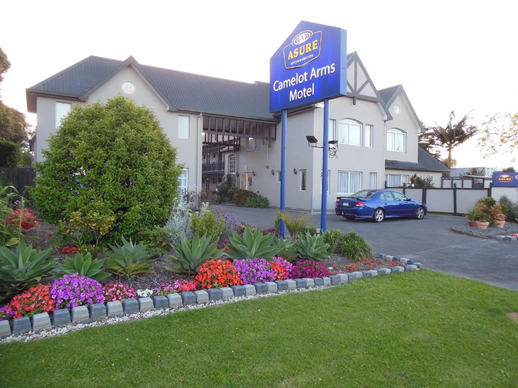 a sign in front of a hotel with flowers at ASURE Camelot Arms Motor Lodge in Auckland
