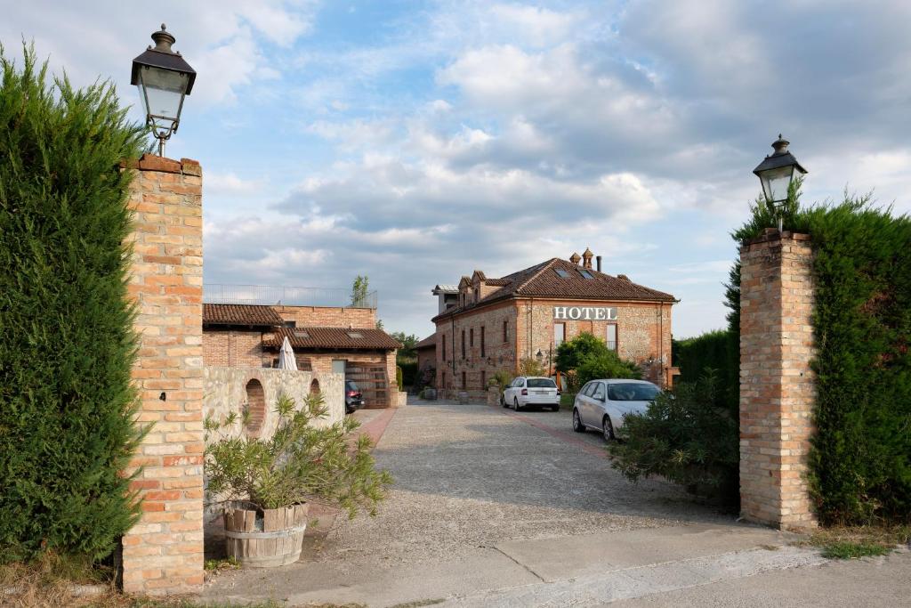 a street with cars parked in front of a building at Hotel Le Botti in Guarene