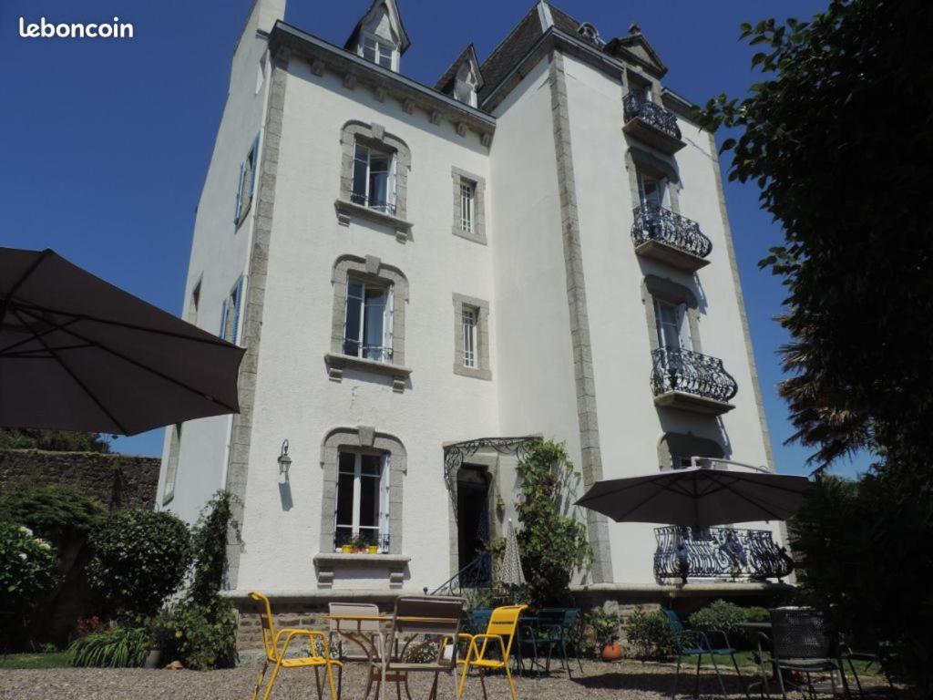 un bâtiment avec des tables et des parasols devant lui dans l'établissement Maison Castel Braz, à Pont-Aven