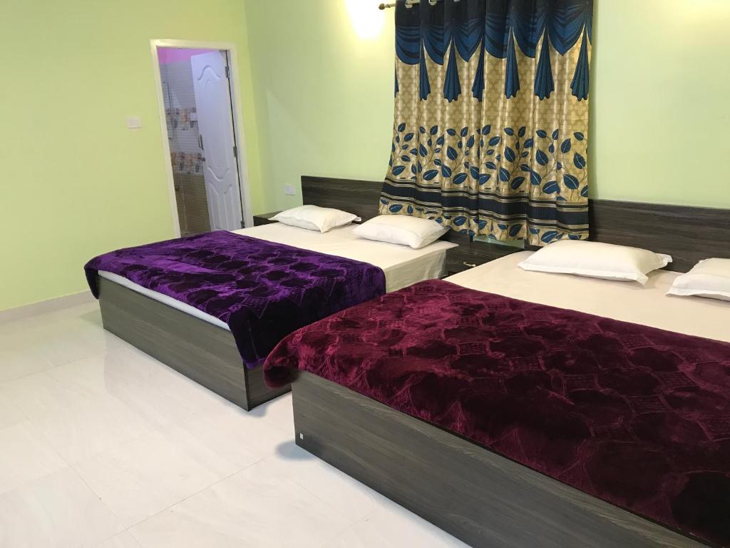 2 bedden in een kamer met paarse lakens bij HAPPYSTAY rooms and cottages in Ooty