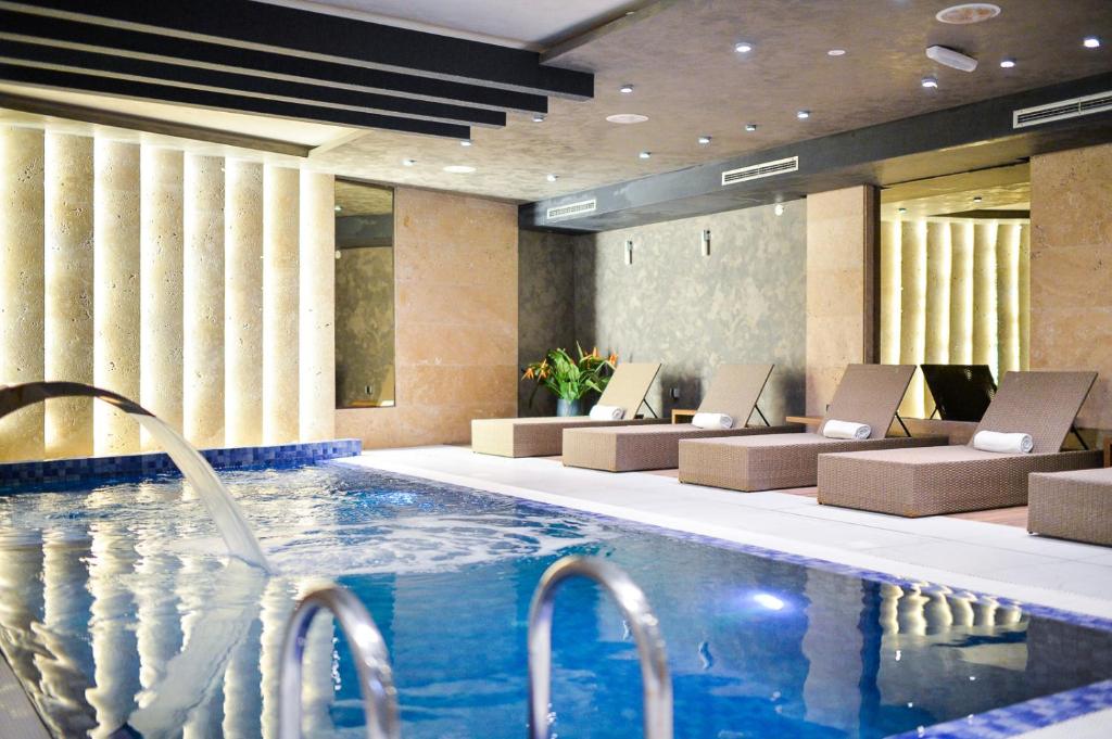 a hotel lobby with a swimming pool and chairs at Amsterdam Hotel in Belgrade
