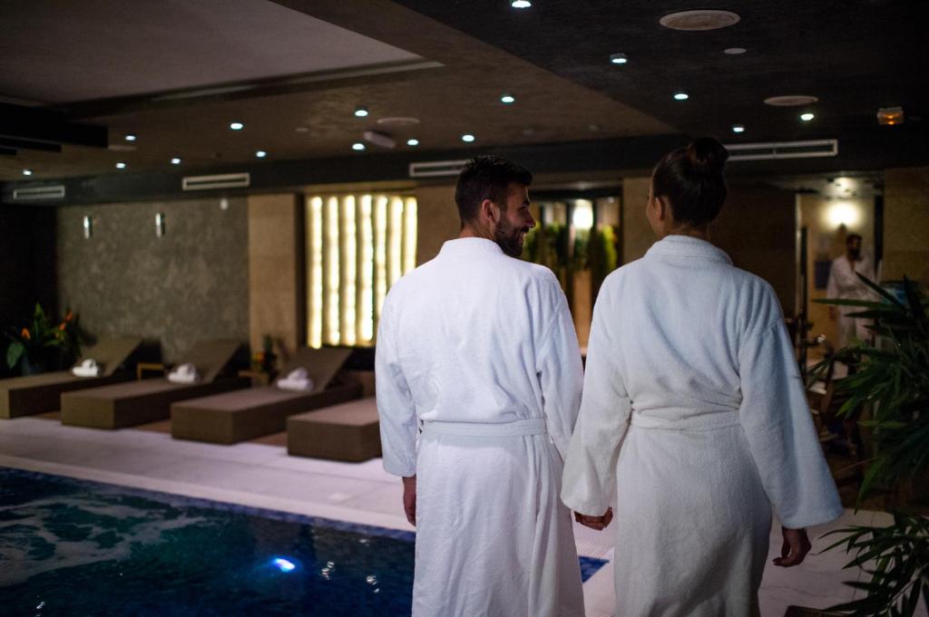 two men in white robes standing next to a swimming pool at Amsterdam Hotel in Belgrade