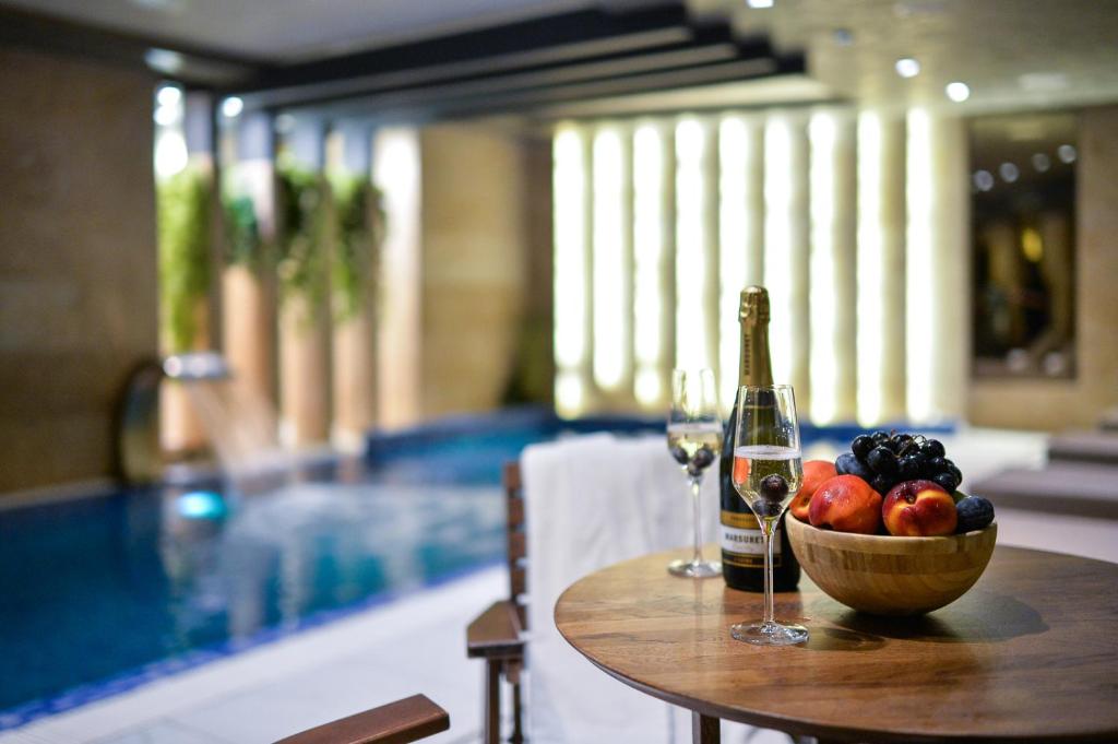 a table with a bowl of fruit and a bottle of wine at Amsterdam Hotel in Belgrade