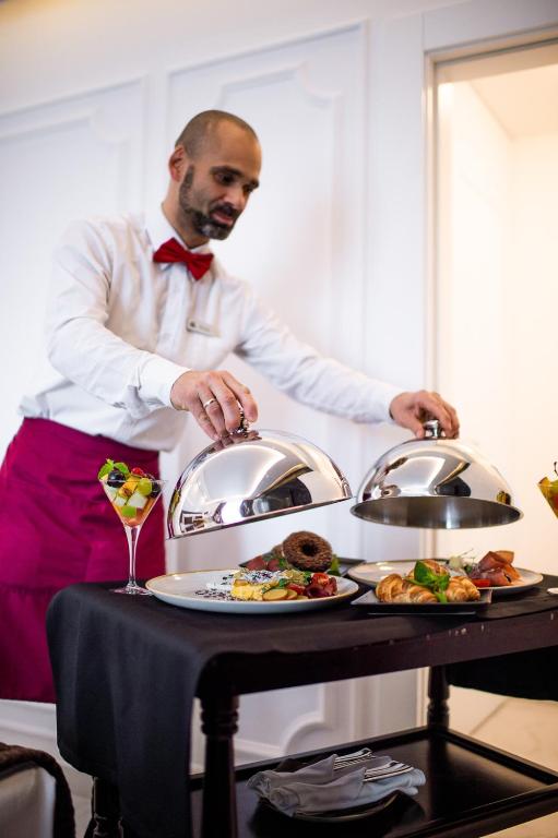 a man standing next to a table with a plate of food at Amsterdam Hotel in Belgrade