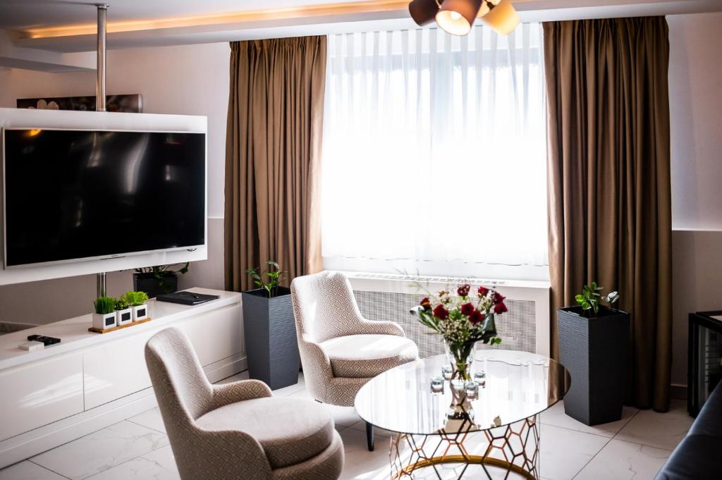 a living room with a table and chairs and a tv at Amsterdam Hotel in Belgrade
