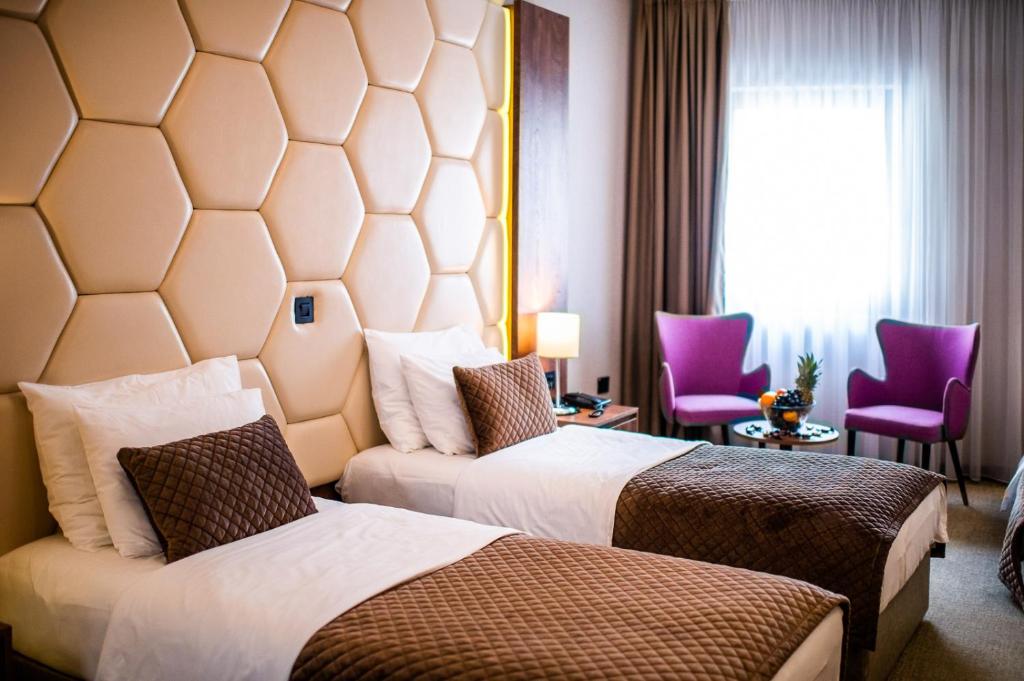 two beds in a hotel room with purple chairs at Amsterdam Hotel in Belgrade