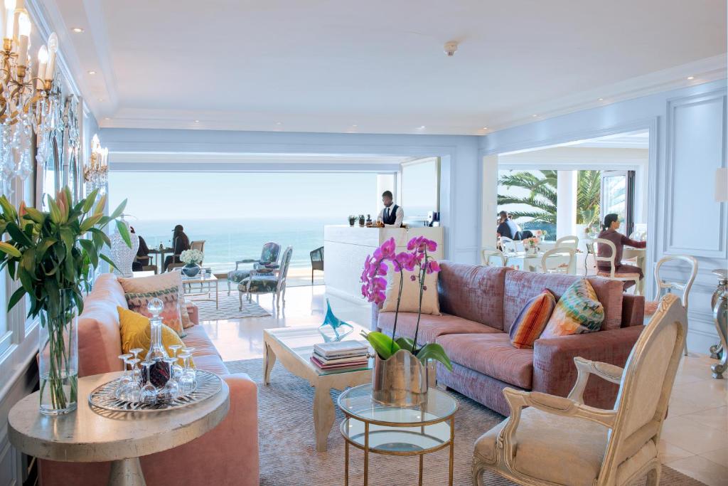a living room with couches and tables and the ocean at The Clarendon - Bantry Bay in Cape Town