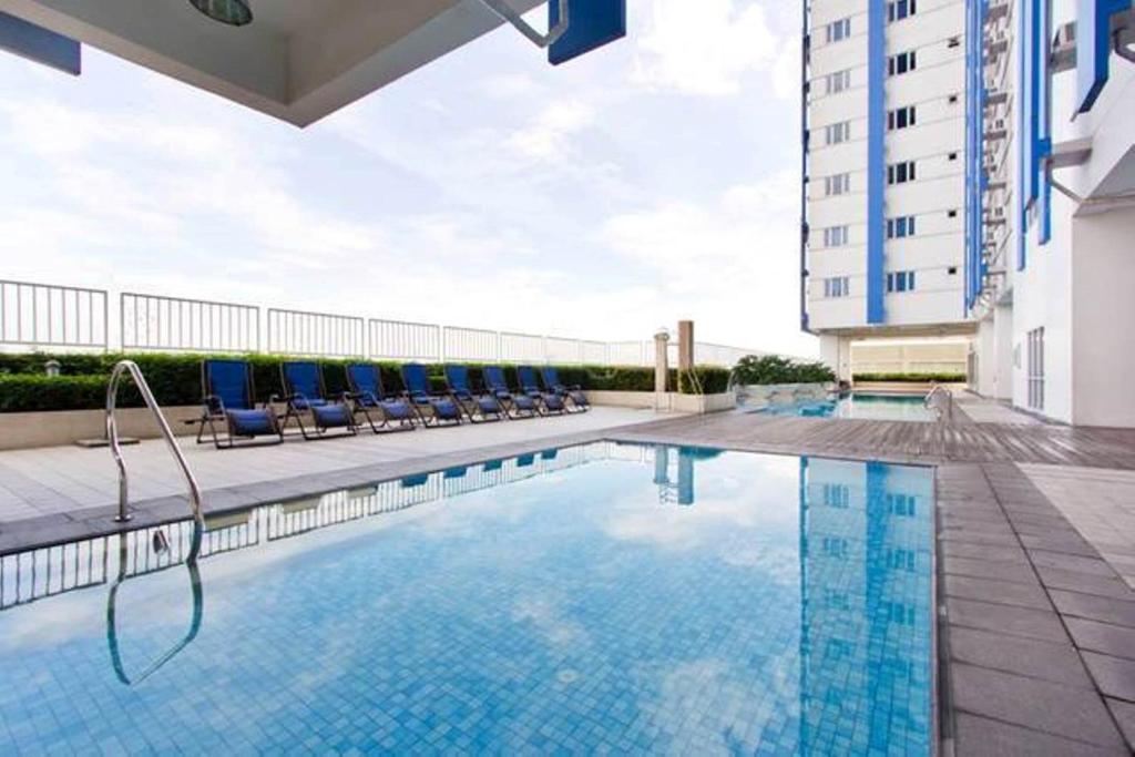 uma piscina de hotel com cadeiras e um edifício em Condo Studio Luxe in Princeton Residences em Manila