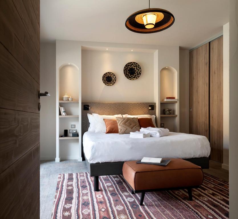 a bedroom with a large bed and a brown stool at Résidence Ynycio in Tignes