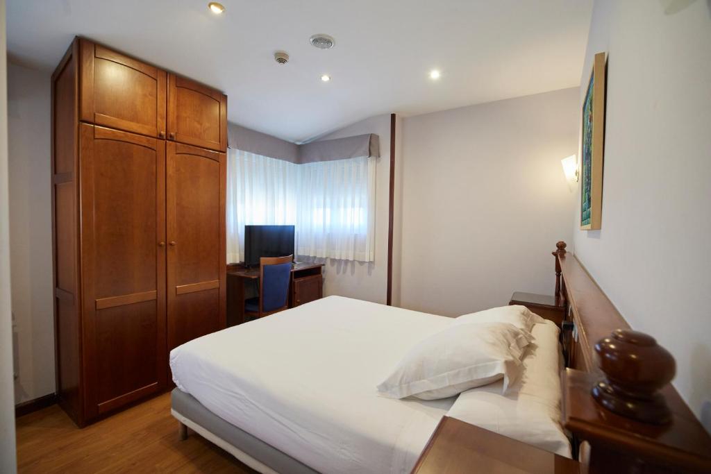 1 dormitorio con 1 cama y armario de madera en Hotel Villalegre, en Avilés