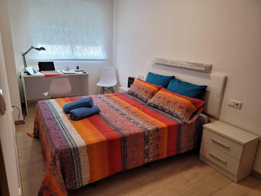 a bedroom with a bed and a desk with a laptop at El Palmar in Murcia