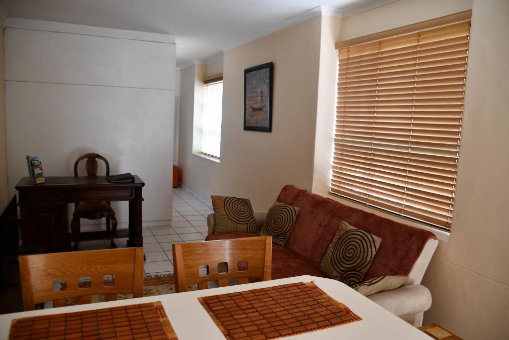sala de estar con sofá, mesa y sillas en Bradclin Sport Newlands, en Ciudad del Cabo