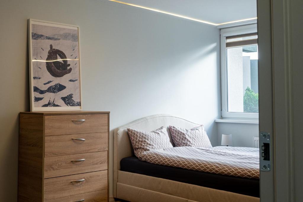 um quarto com uma cama, uma cómoda e uma janela em DAILY Apartment em Anykščiai