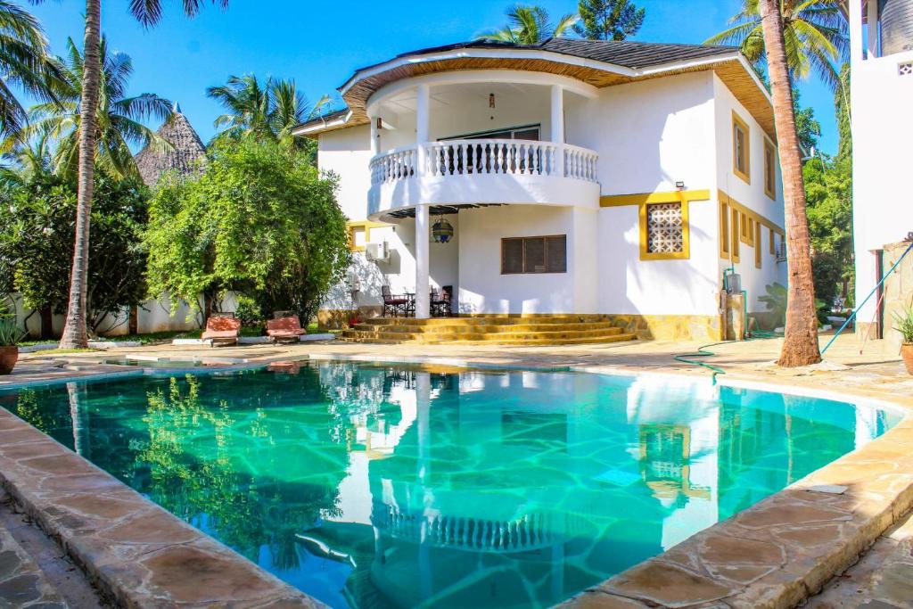 a villa with a swimming pool in front of a house at Tichi Villas - Diani Beach in Diani Beach