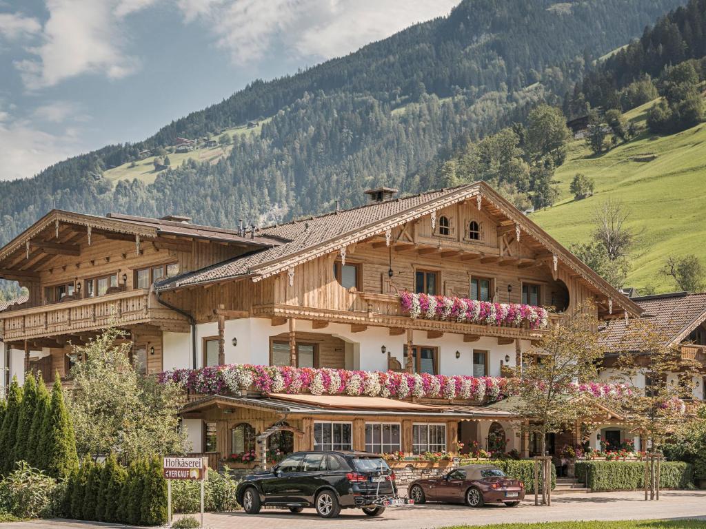a large wooden house with two cars parked in front of it at Hotel Garni Larcherhof in Mayrhofen