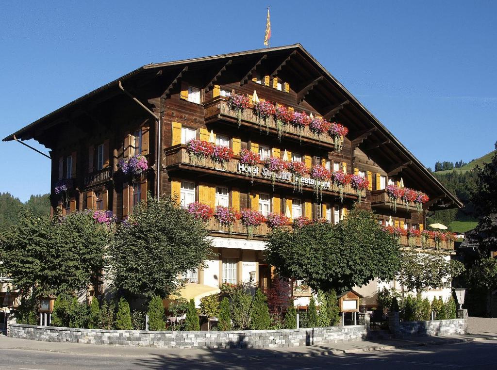 un grand bâtiment avec des boîtes de fleurs à l'avant dans l'établissement Hotel Saanerhof, à Gstaad
