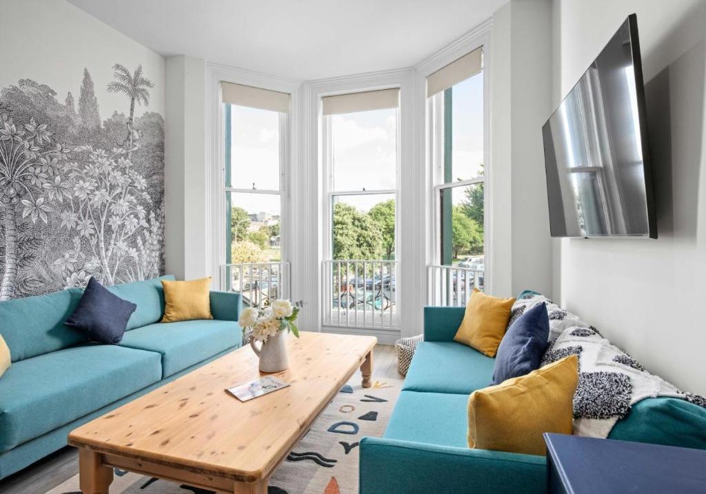 a living room with blue couches and a wooden table at The Narrow House - Free Parking By My Getaways in Brighton & Hove
