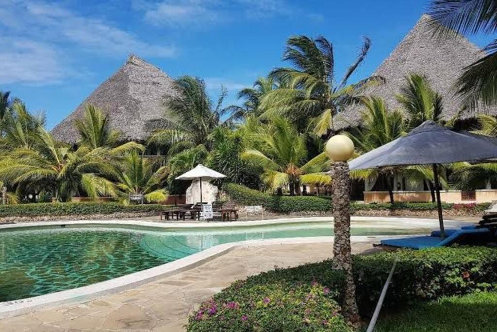 un complexe avec une piscine et des palmiers dans l'établissement Baharini Beachfront Cottage, à Malindi