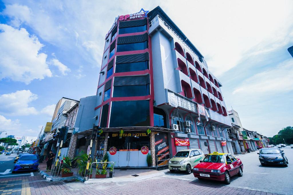 a tall building with cars parked in front of it at SP Star Hotel in Sungai Petani