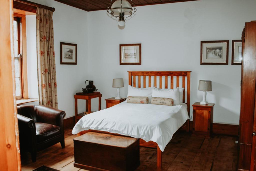 1 dormitorio con 1 cama y 1 silla en Swartvlei Guest Farm en Sedgefield