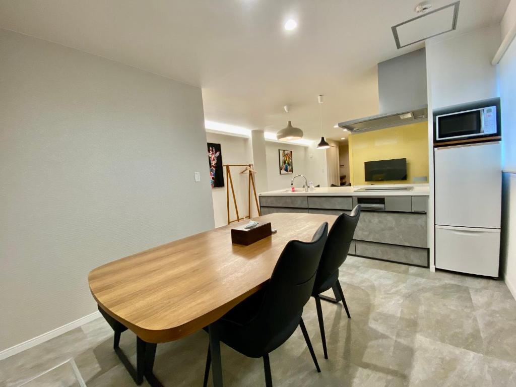 a kitchen with a wooden table and black chairs at Villa Monica in Nagoya