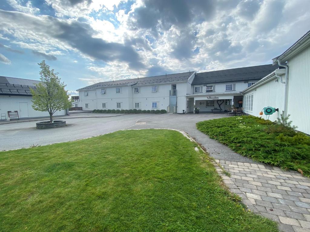 a large white building with a grass yard at Skaslien Hotel & Guesthouse in Kirkenær