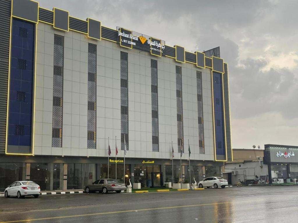 a large building with cars parked in front of it at جوهرة السراة للأجنحة الفندقية in Khamis Mushayt