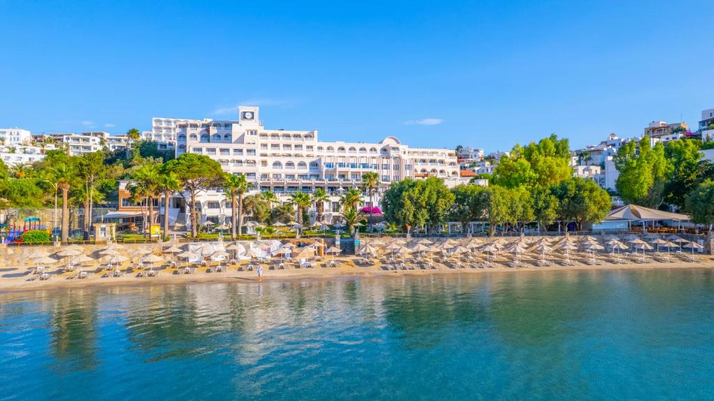 a beach with chairs and umbrellas and a city at Azka Hotel in Bodrum City