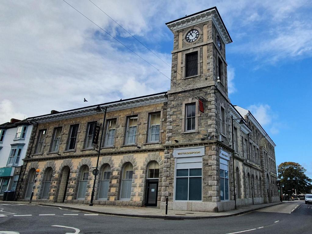 un bâtiment avec une tour d'horloge en haut dans l'établissement The John Francis Basset Wetherspoon, à Camborne