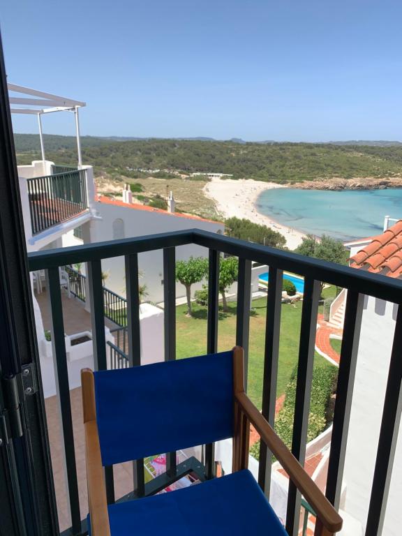 uma varanda com uma cadeira azul e vista para a praia em Apartamento en frente de la playa em Son Parc