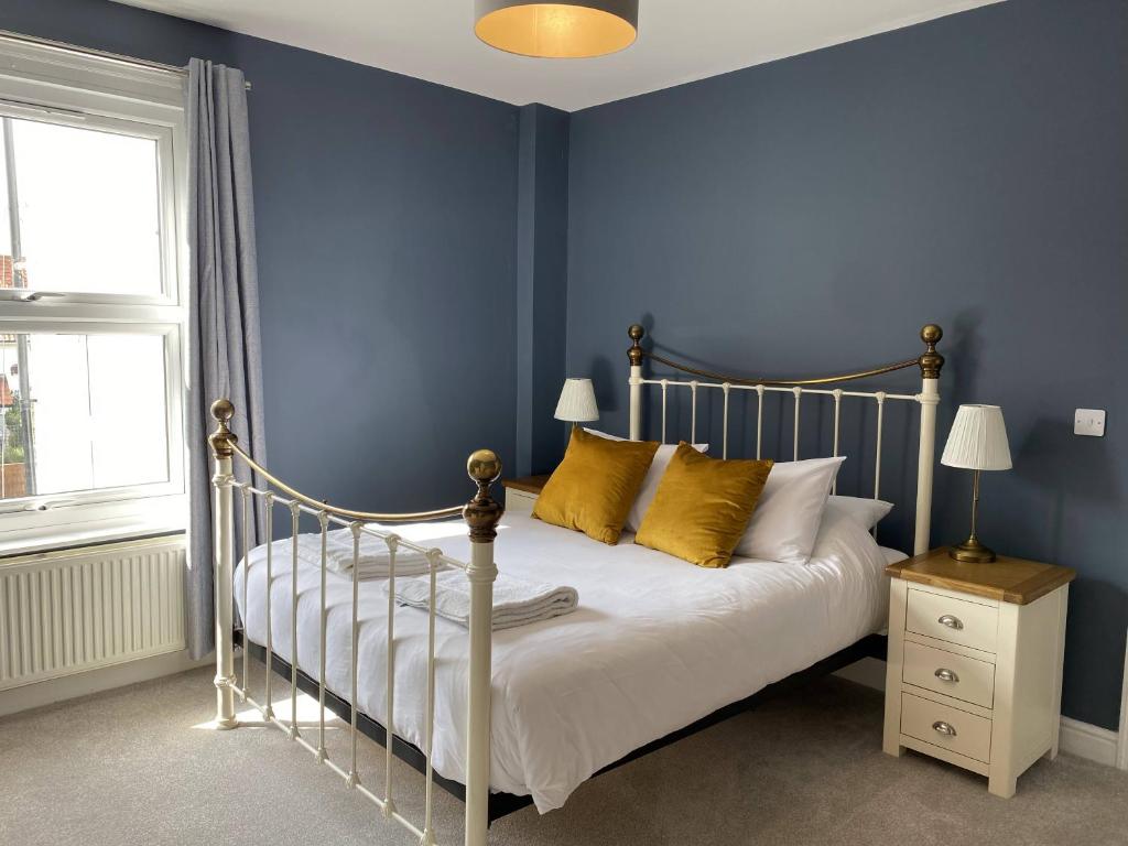 a bedroom with blue walls and a bed with yellow pillows at Coast House Cromer - Sleeps 15, hot tub, sea views in Cromer