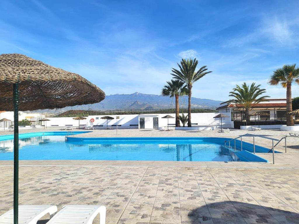 einen Pool mit Sonnenschirm und Palmen in der Unterkunft Casa Diana by HelloApartments in Costa Del Silencio