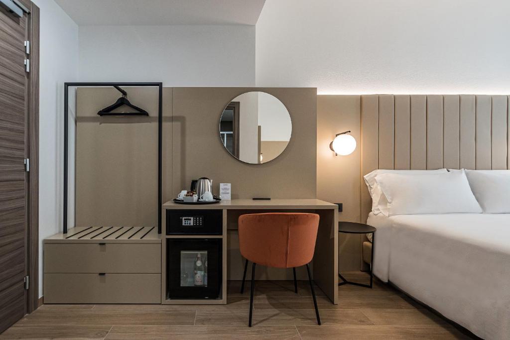 a hotel room with a bed and a desk with a mirror at BB Hotels Smarthotel Duomo in Milan