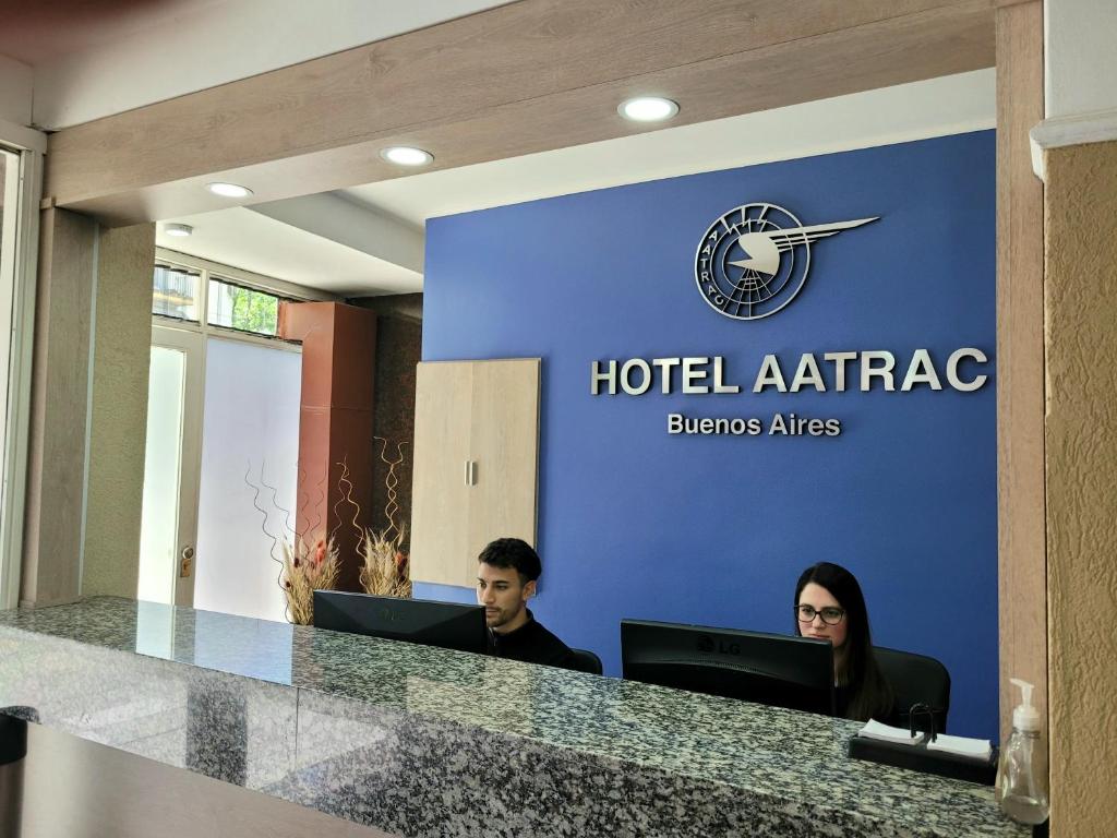 布宜諾斯艾利斯的住宿－Hotel AATRAC Buenos Aires，两人坐在酒店办公室的办公桌上