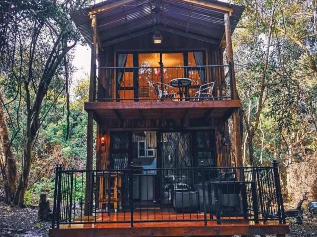 a tree house with a balcony in the woods at SHABBY FUFU LIFESTYLE FARM in Plettenberg Bay