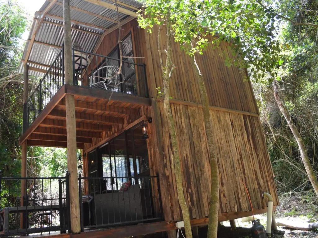 a tree house with a balcony in the woods at SHABBY FUFU LIFESTYLE FARM in Plettenberg Bay