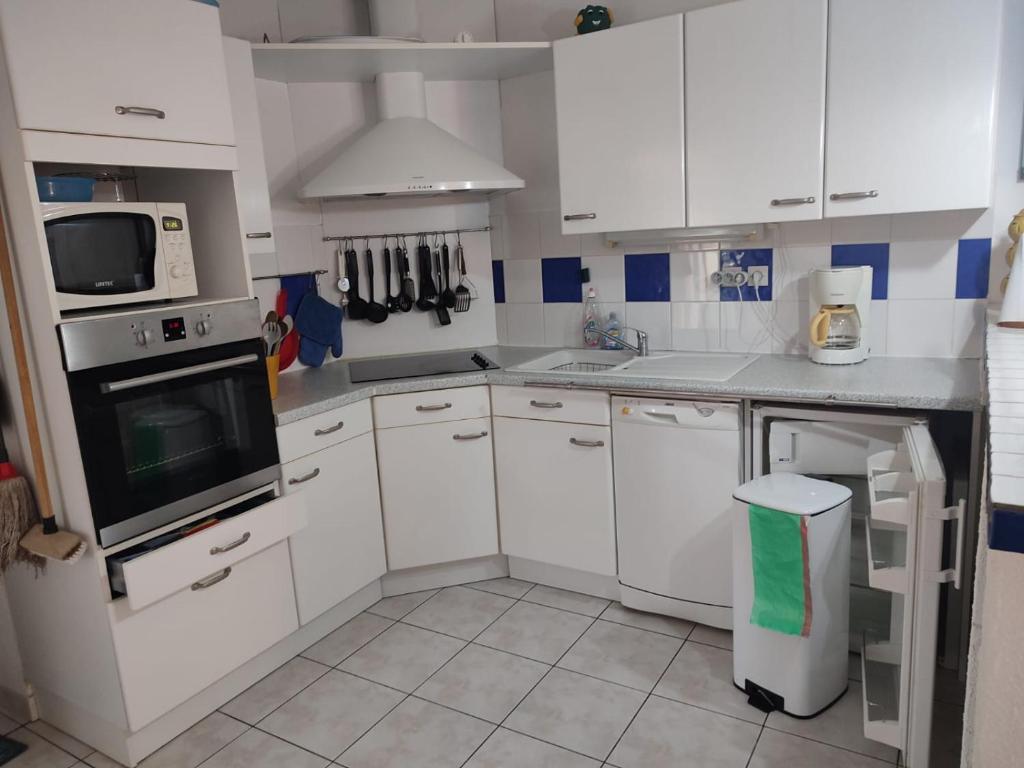 a kitchen with white cabinets and a stove top oven at Mas de la garrigue 13 in Saint Pierre La Mer