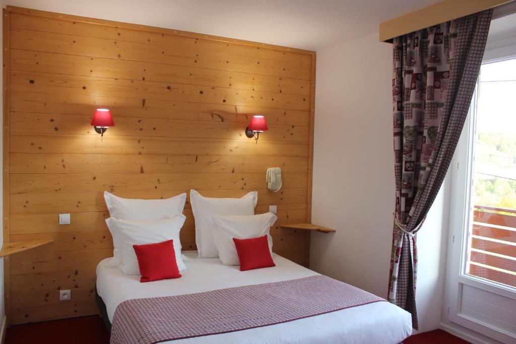 a bedroom with a large white bed with red pillows at Hôtel Les Charmilles in Besse-et-Saint-Anastaise