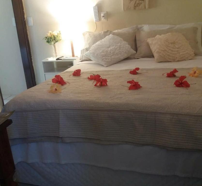 a bed with red rose petals on it at Casa da Marluce in Fernando de Noronha