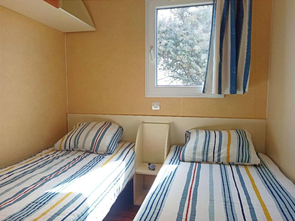 2 Betten in einem kleinen Zimmer mit Fenster in der Unterkunft Casitas Mobil Home in Mazo