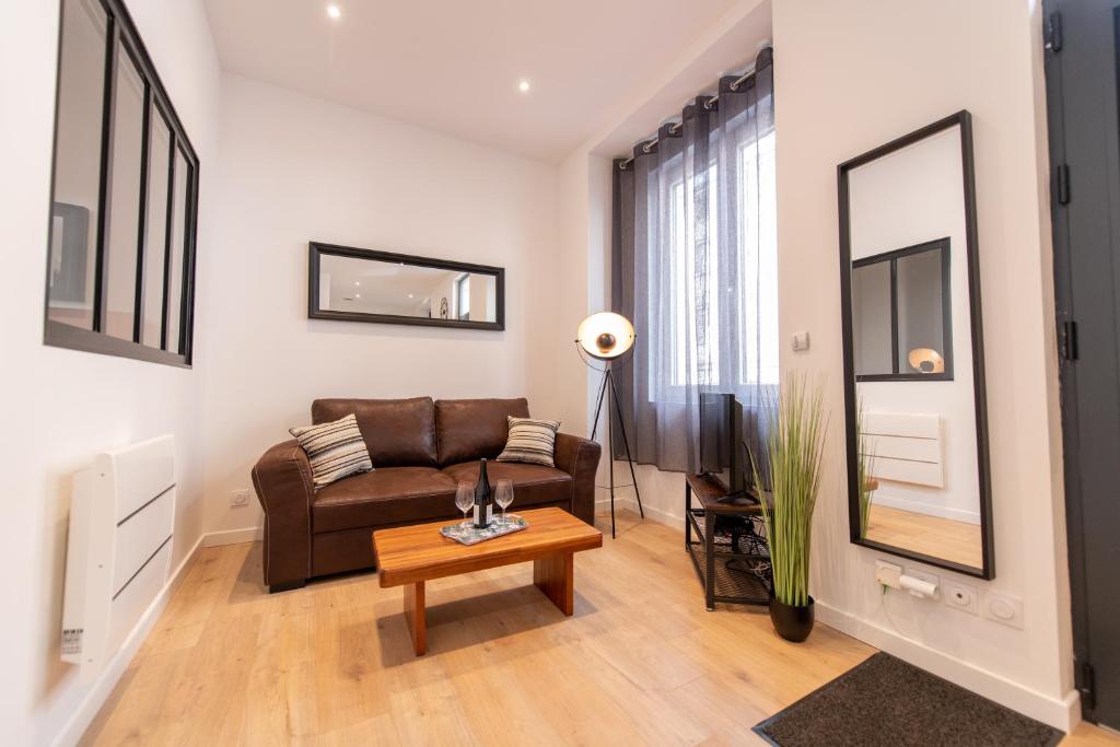 uma sala de estar com um sofá castanho e uma mesa em KASA LOFT CENTRE 2 - WIFI et TV - Confortable et stationnement gratuit à proximité em Saint-Étienne