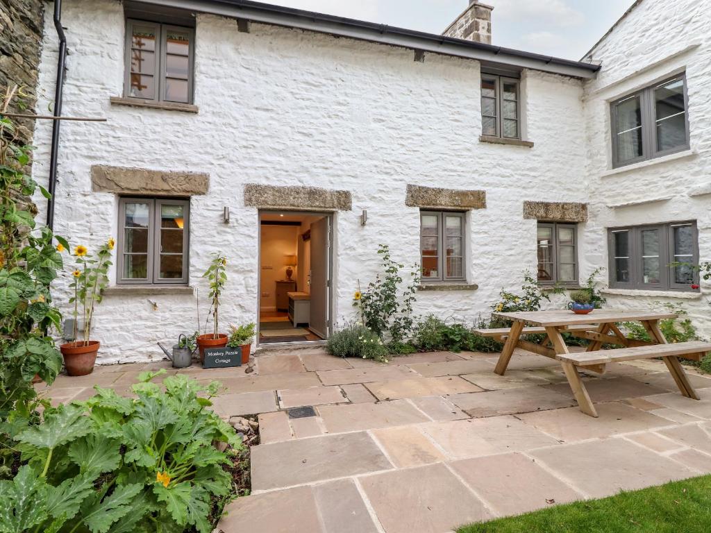 a stone patio in front of a white building at Monkey Puzzle Cottage in Sedbergh