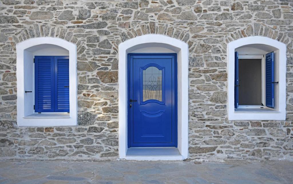 a blue door and two windows on a stone wall at Armenistis appartments with a view in Armenistis
