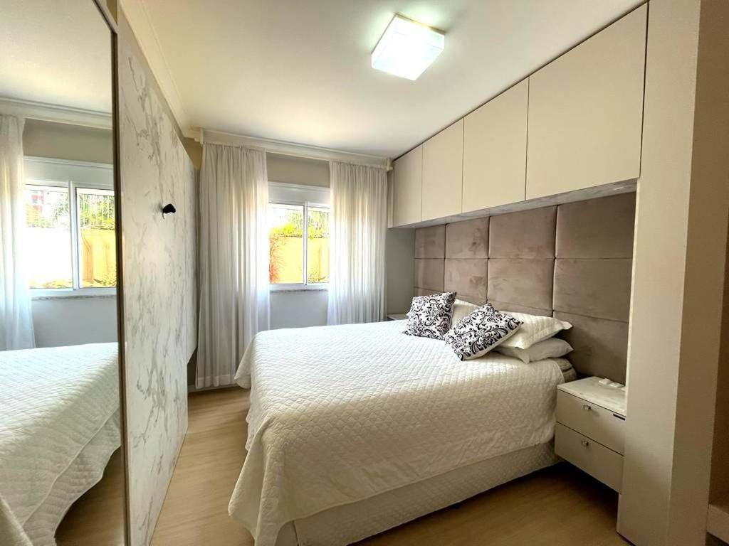 een slaapkamer met 2 bedden en 2 ramen bij Apartamento Villa Nova Master Collection in Passo Fundo