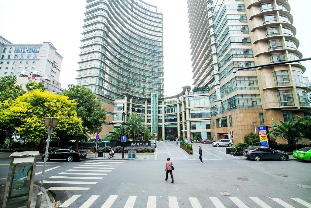 a man crossing a street in a city with tall buildings at Westlake 7 Service Apartment in Hangzhou