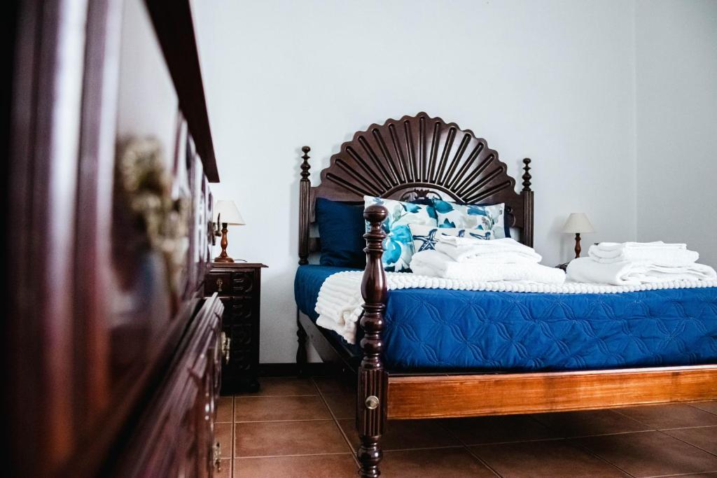 a bedroom with a bed with blue and white pillows at Apartamento Bela Vista Ilha Terceira in Feteira